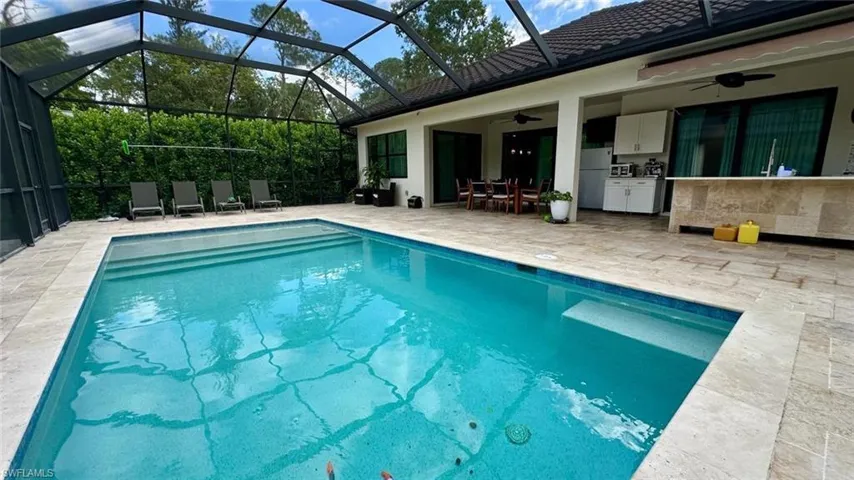 Swimming pool with a patio, a lanai, exterior kitchen, outdoor dining area, and a sunroom