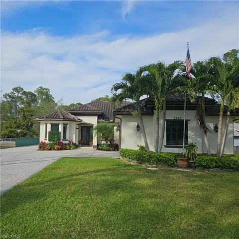 View of front of property with a front lawn, stucco siding, driveway, and a tile roof