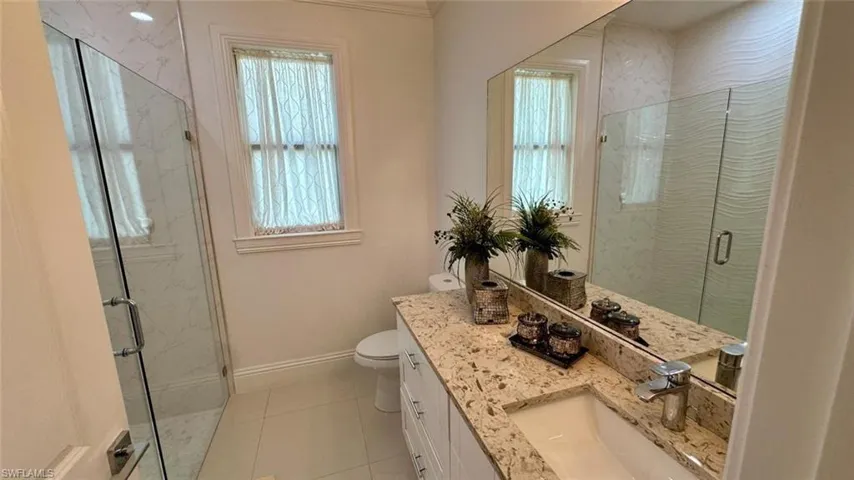 Bathroom featuring vanity, a marble finish shower, and light tile patterned floors