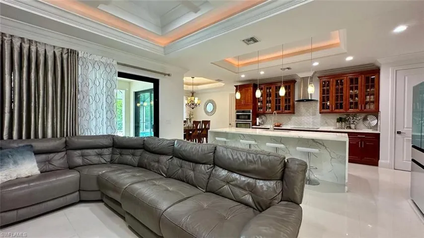 Living area featuring a chandelier, ornamental molding, a raised ceiling, and light tile patterned flooring
