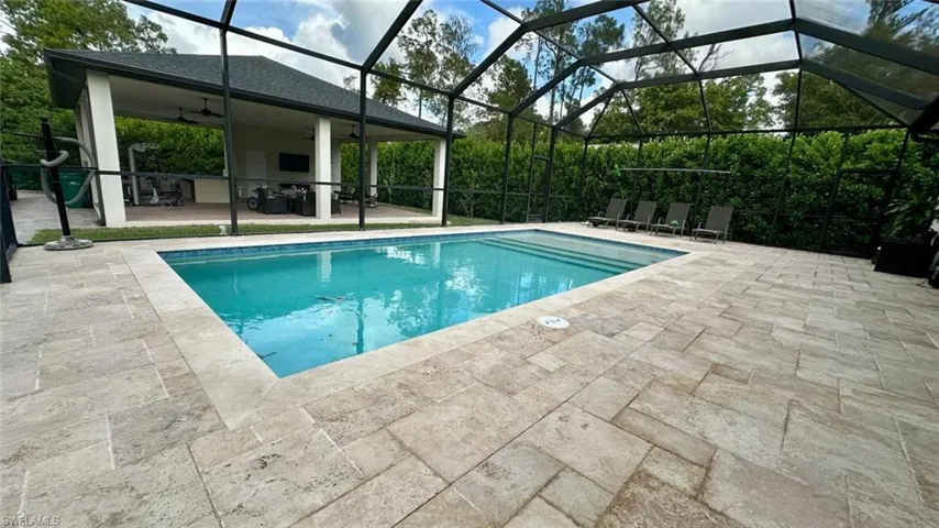 Swimming pool featuring glass enclosure, a patio, and a sunroom