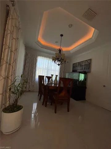 Dining area with a chandelier, a raised ceiling, and crown molding