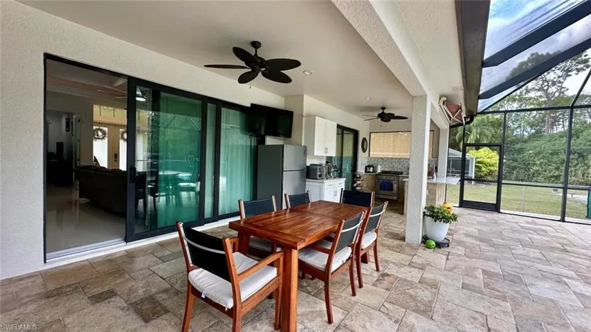 Sunroom featuring area for grilling, outdoor dining space, a patio, and a ceiling fan