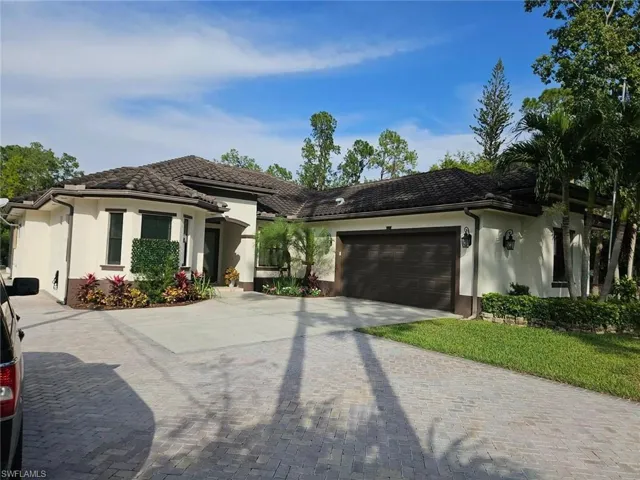 View of front of property with stucco siding, decorative driveway, a garage, and a tile roof