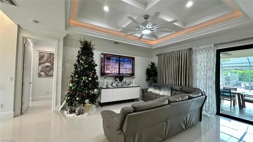 Living area featuring ornamental molding, coffered ceiling, a ceiling fan, tile patterned floors, and beamed ceiling