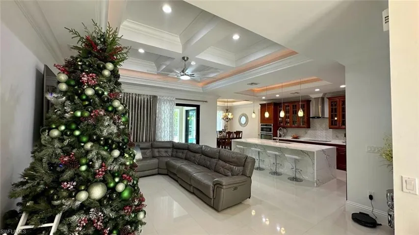 Living area with ornamental molding, coffered ceiling, ceiling fan, beamed ceiling, and recessed lighting