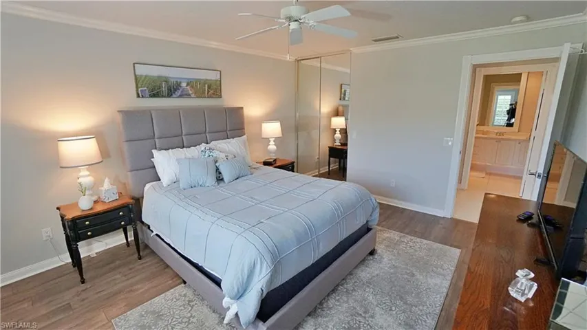 Bedroom with crown molding, a closet, wood-type flooring, ceiling fan, and connected bathroom
