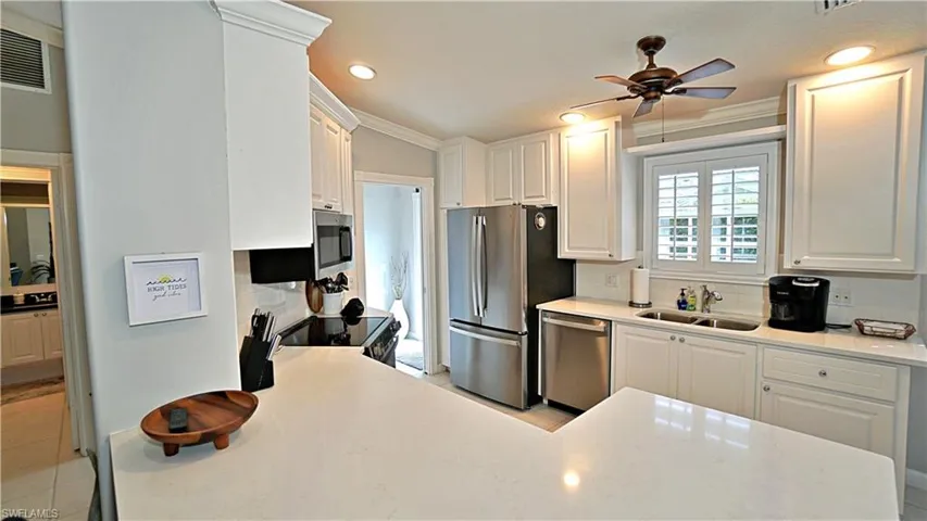 Kitchen with ceiling fan, sink, appliances with stainless steel finishes, and white cabinets