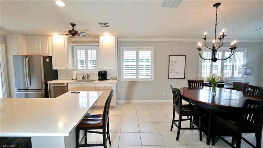 Kitchen featuring ceiling fan with notable chandelier, white cabinets, appliances with stainless steel finishes, and decorative light fixtures