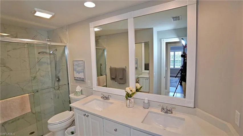 Bathroom featuring a shower with door, vanity, and toilet