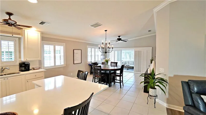 Tiled dining area featuring ceiling fan with notable chandelier, plenty of natural light, and ornamental molding