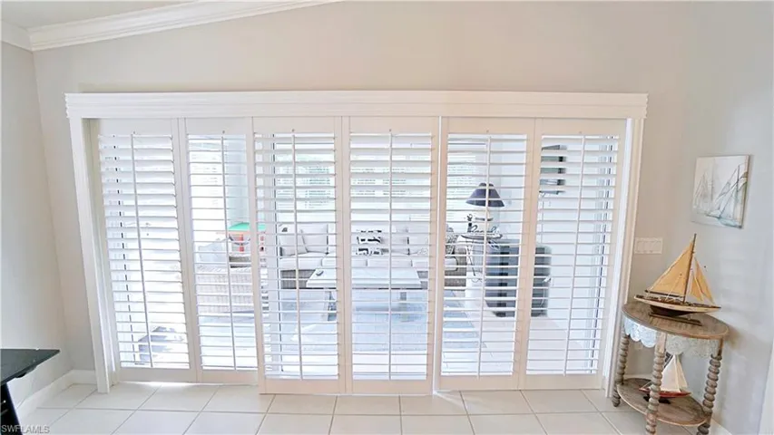 Entryway with crown molding, vaulted ceiling, and light tile patterned flooring