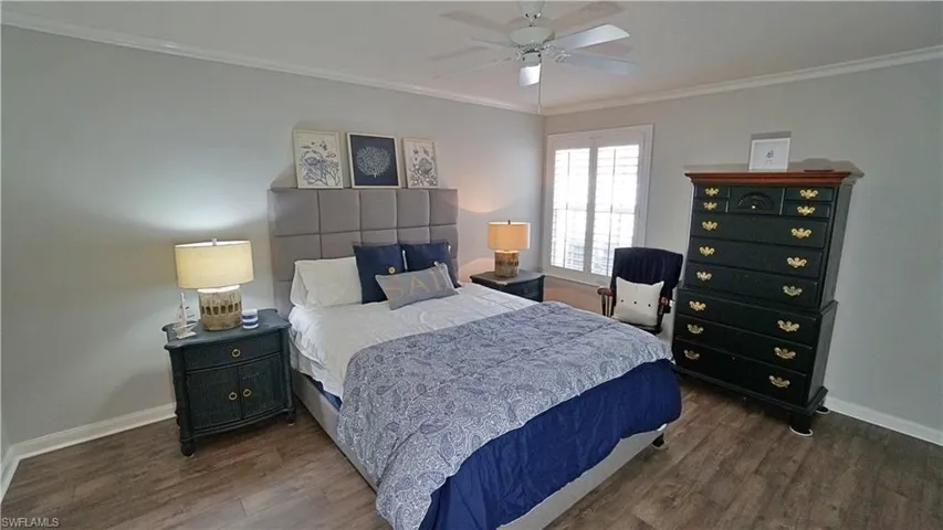 Bedroom with ceiling fan, dark hardwood / wood-style flooring, and ornamental molding