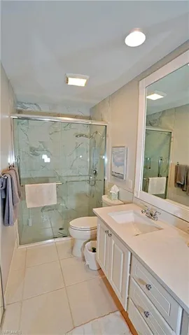 Bathroom featuring tile patterned floors, walk in shower, toilet, and vanity