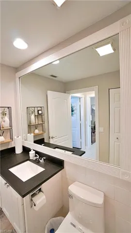 Bathroom with tile walls, toilet, vanity, and tile patterned floors