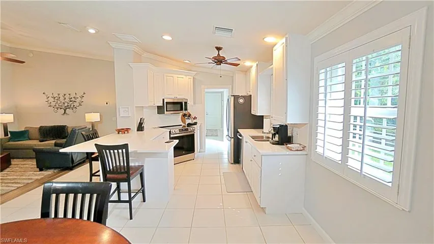 Kitchen featuring appliances with stainless steel finishes, plenty of natural light, a kitchen bar, and ceiling fan