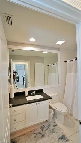 Bathroom featuring vanity, toilet, curtained shower, and tile patterned floors