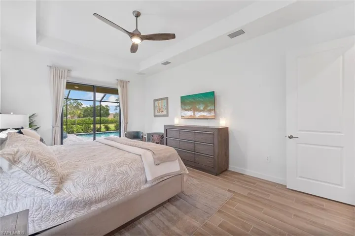 Bedroom with access to exterior, baseboards, visible vents, light wood-style floors, and a raised ceiling
