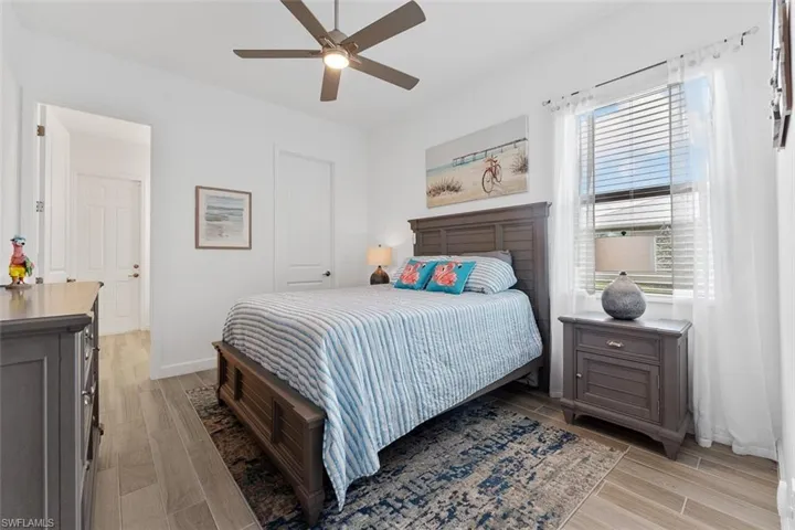 Bedroom featuring light wood finished floors, baseboards, and a ceiling fan