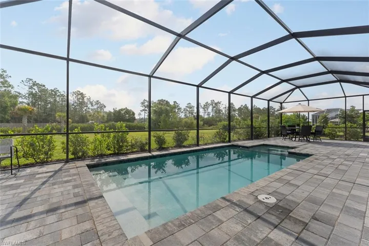 Outdoor pool featuring glass enclosure and a patio