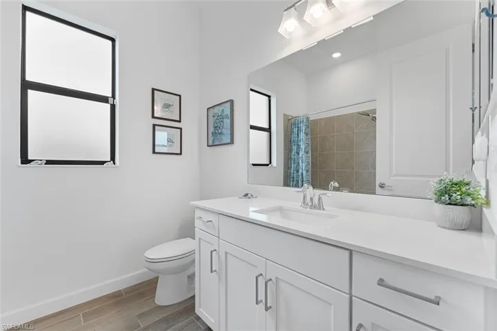 Full bathroom with toilet, baseboards, wood finished floors, curtained shower, and vanity