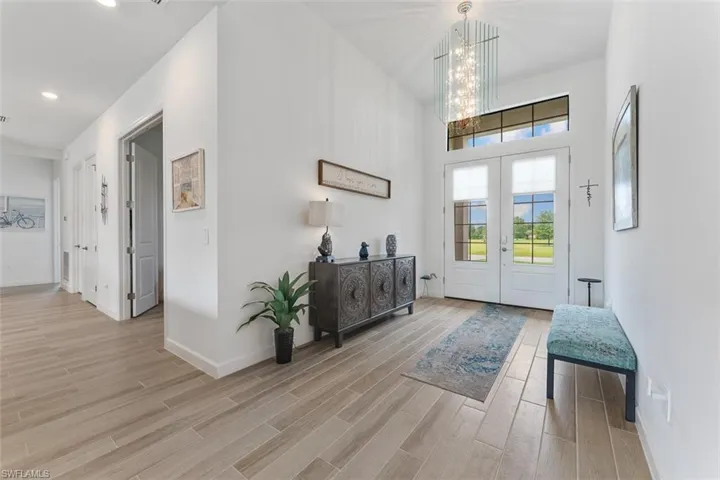 Foyer entrance featuring an inviting chandelier, french doors, light wood finished floors, and baseboards