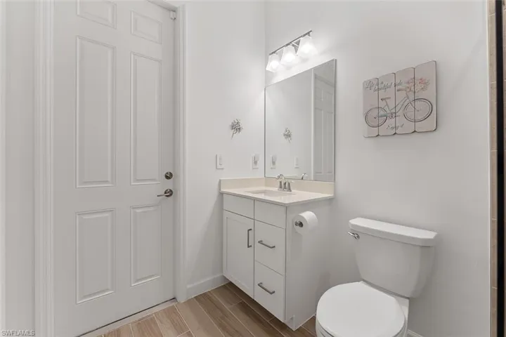 Bathroom featuring toilet, vanity, wood finished floors, and baseboards