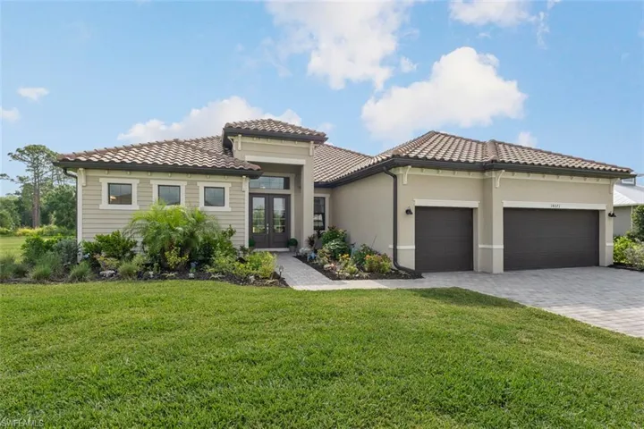 View of front of house with a tiled roof, an attached garage, french doors, decorative driveway, and a front yard