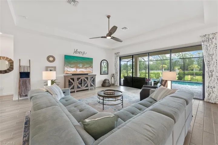 Living room with ceiling fan, a healthy amount of sunlight, a tray ceiling, and visible vents