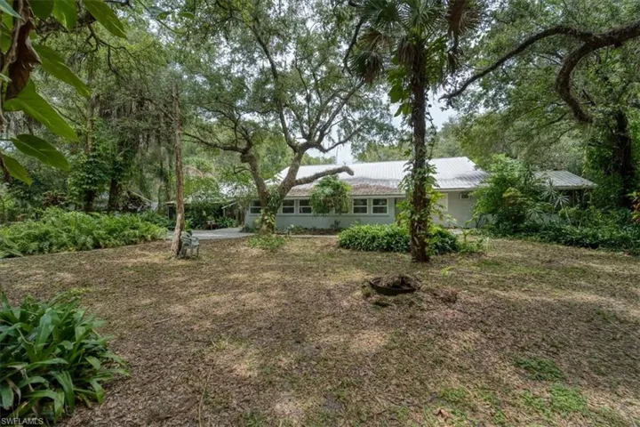 Rear view of home and oak covered renced back yard