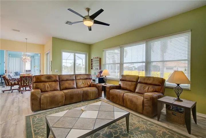 Living area with ceiling fan with notable chandelier, visible vents, and wood finished floors