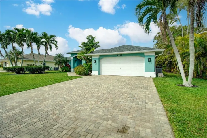 Single story home with stucco siding, a garage, a front lawn, and decorative driveway