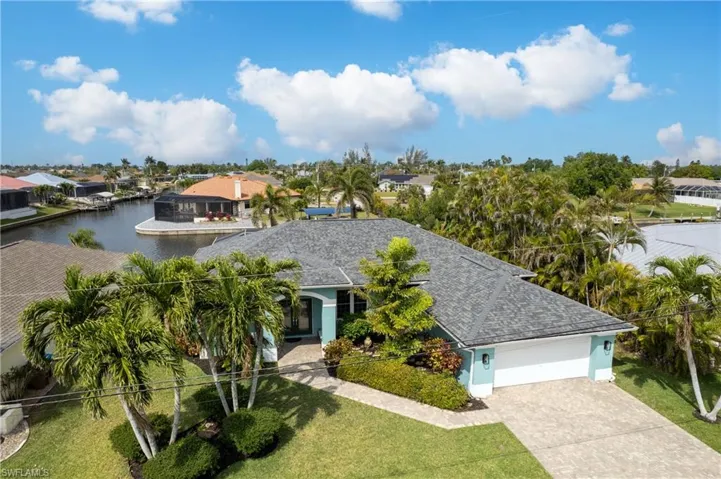View of front facade featuring driveway, a front yard, stucco siding, a shingled roof, and a garage