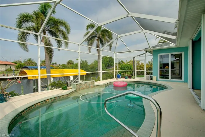 Outdoor pool featuring a water view, a lanai, a hot tub, and a patio