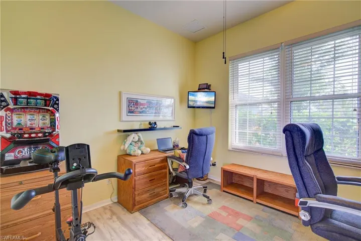 Home office with wood finished floors, baseboards, and visible vents