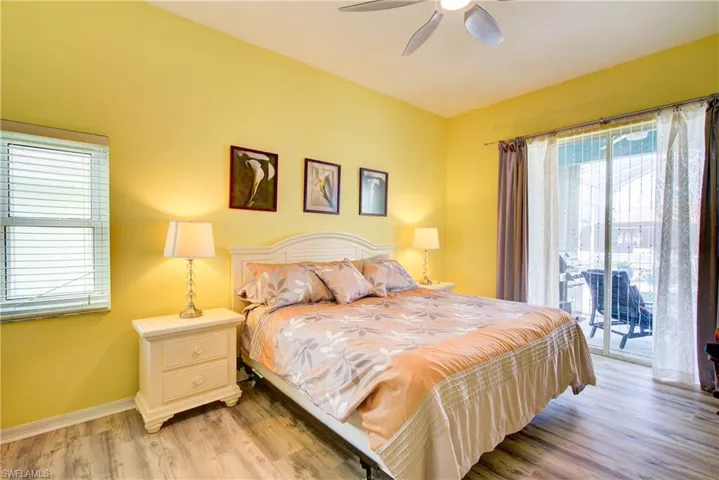 Bedroom with light wood finished floors, baseboards, access to exterior, and ceiling fan