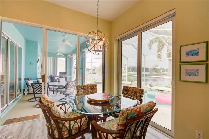 Dining space with a water view, ceiling fan with notable chandelier, and light wood-style flooring