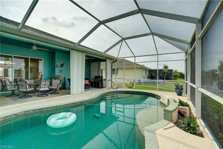 Outdoor pool featuring fence, grilling area, glass enclosure, a ceiling fan, and a patio area