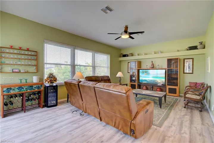 Living area featuring baseboards, beverage cooler, visible vents, ceiling fan, and wood finished floors