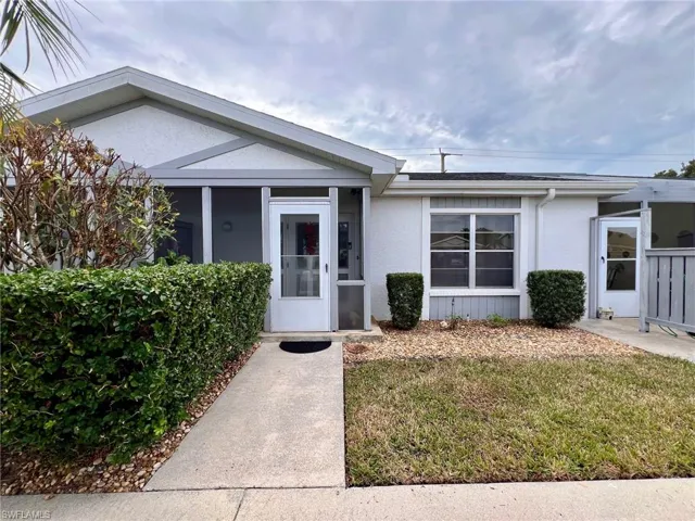 Entrance to property with stucco siding and a lawn
