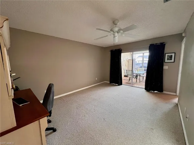 Unfurnished office with a textured ceiling, carpet flooring, and a ceiling fan
