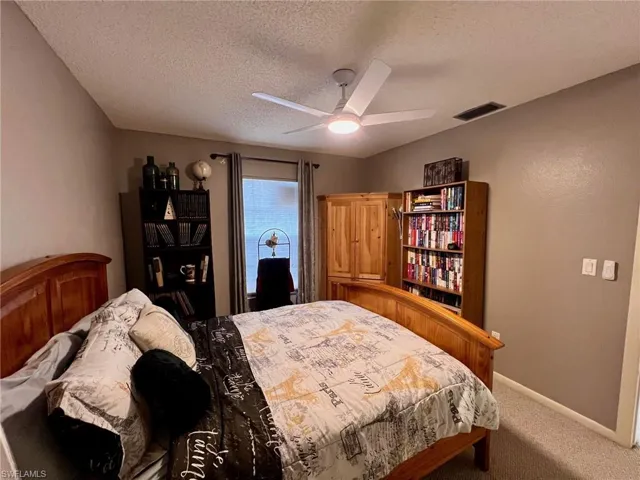 Bedroom featuring carpet, a textured ceiling, and a ceiling fan