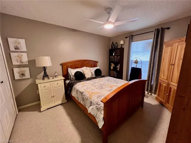 Carpeted bedroom featuring a textured ceiling and a ceiling fan