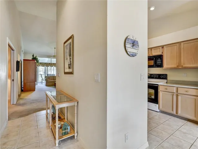 Hallway featuring light tile patterned flooring and light carpet