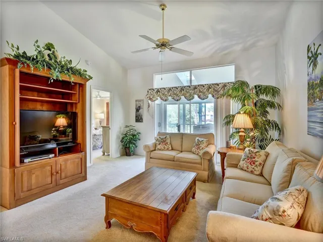 Carpeted living area with lofted ceiling and ceiling fan