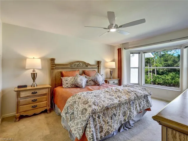 Carpeted bedroom with a ceiling fan and baseboards