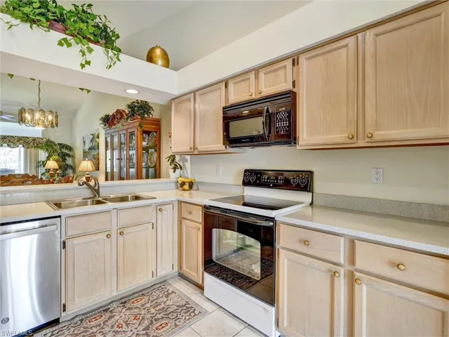 Kitchen featuring light brown cabinets, electric stove, dishwasher, and black microwave