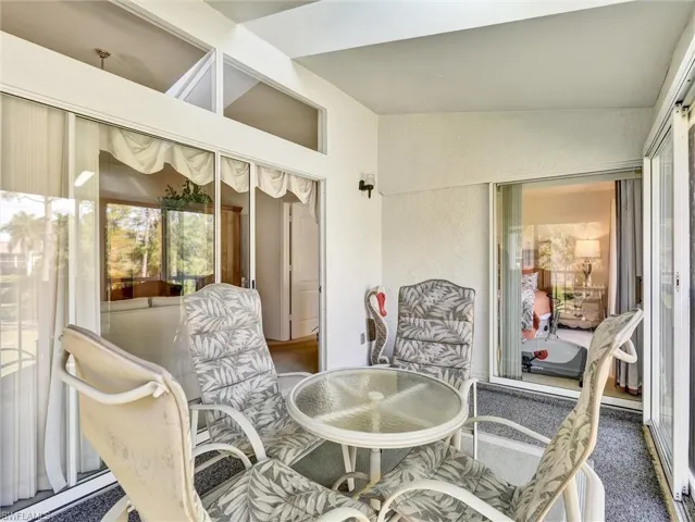 Sunroom featuring lofted ceiling, a textured wall, and carpet floors