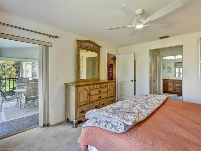 Bedroom featuring light colored carpet, access to exterior, ceiling fan, and ensuite bathroom