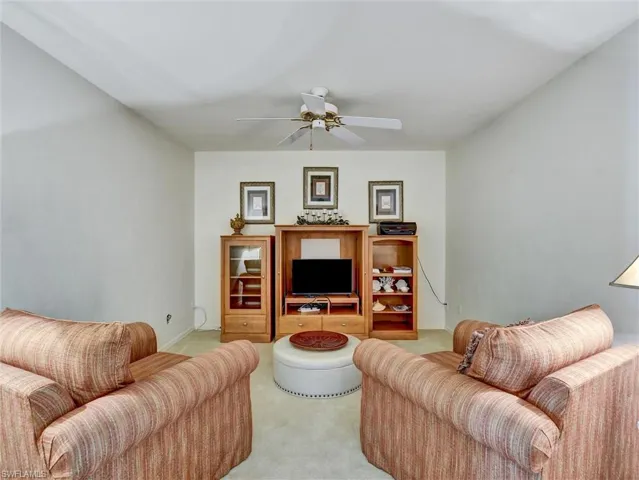 Living area with ceiling fan and light carpet